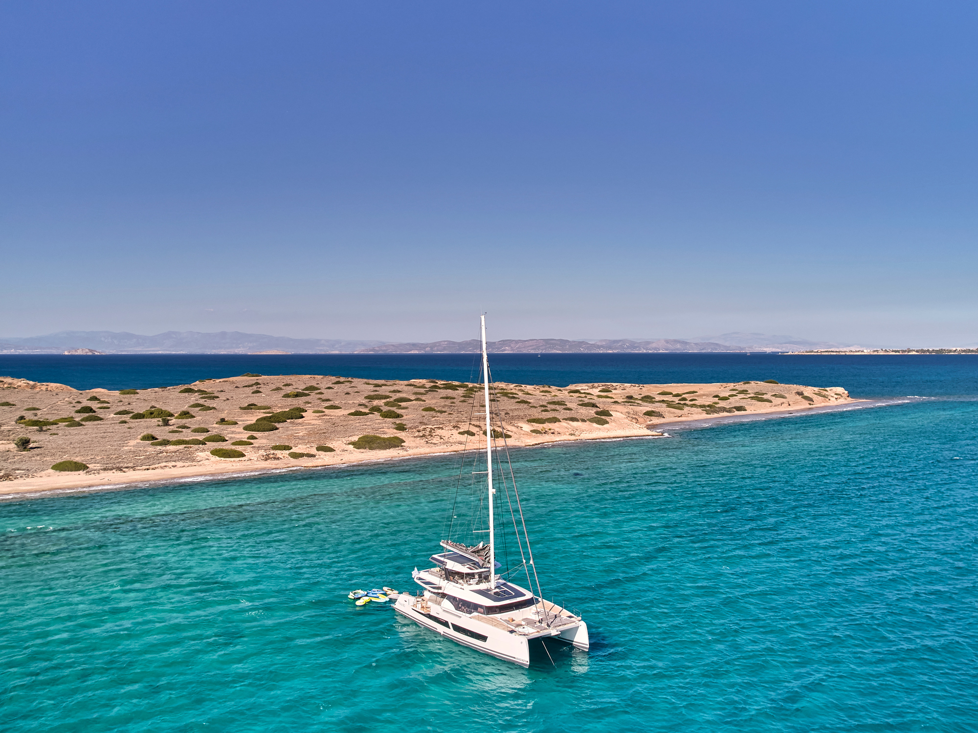 Aerial view of the Fountaine Pajot Thira 80 catamaran with a swimmer entering the water from the swim platform
